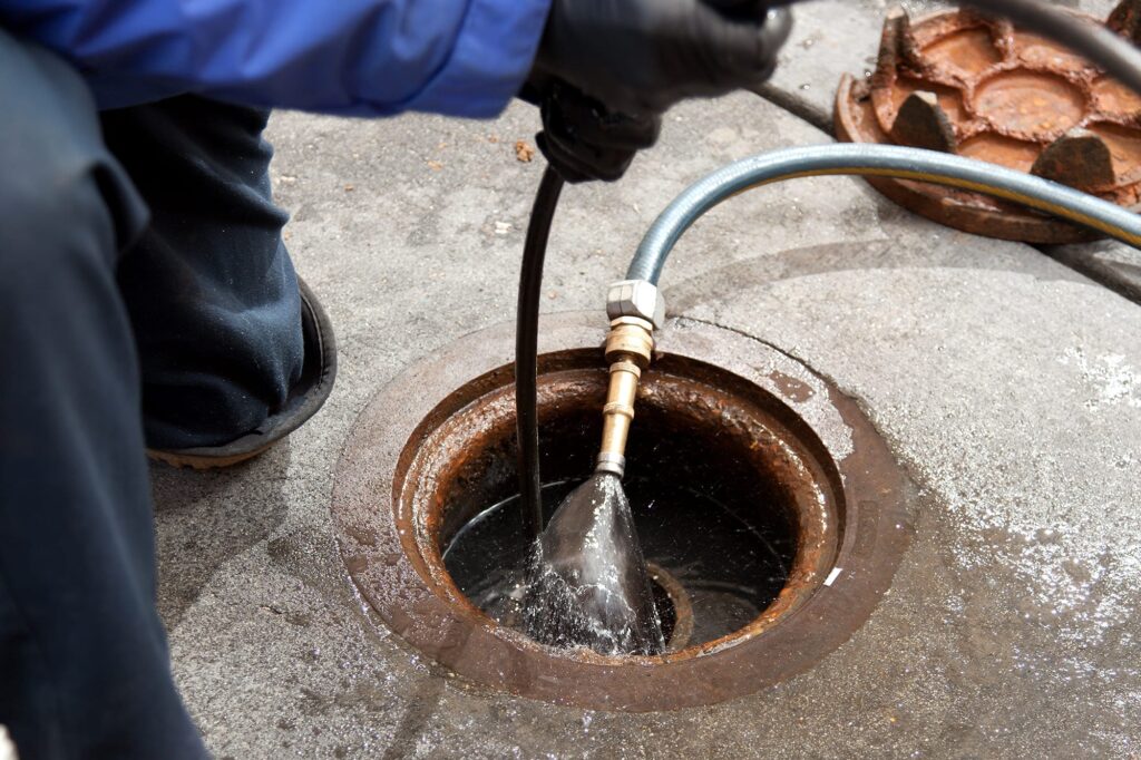 Plumber hydro jetting a sewer line through a manhole in Philadelphia