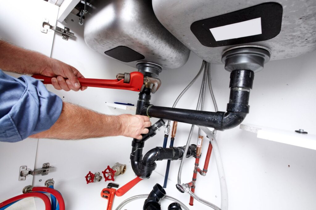 Plumber repairing drain pipes beneath a kitchen sink in Philadelphia
